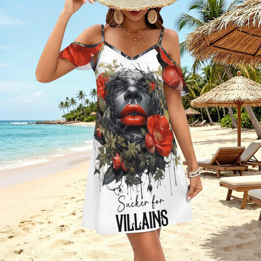 A model wearing the white "Sucker for VILLAINS" ruffle spaghetti strap dress with an edgy dark romance graphic of a woman's face and red roses, styled with a straw sun hat on a beach.