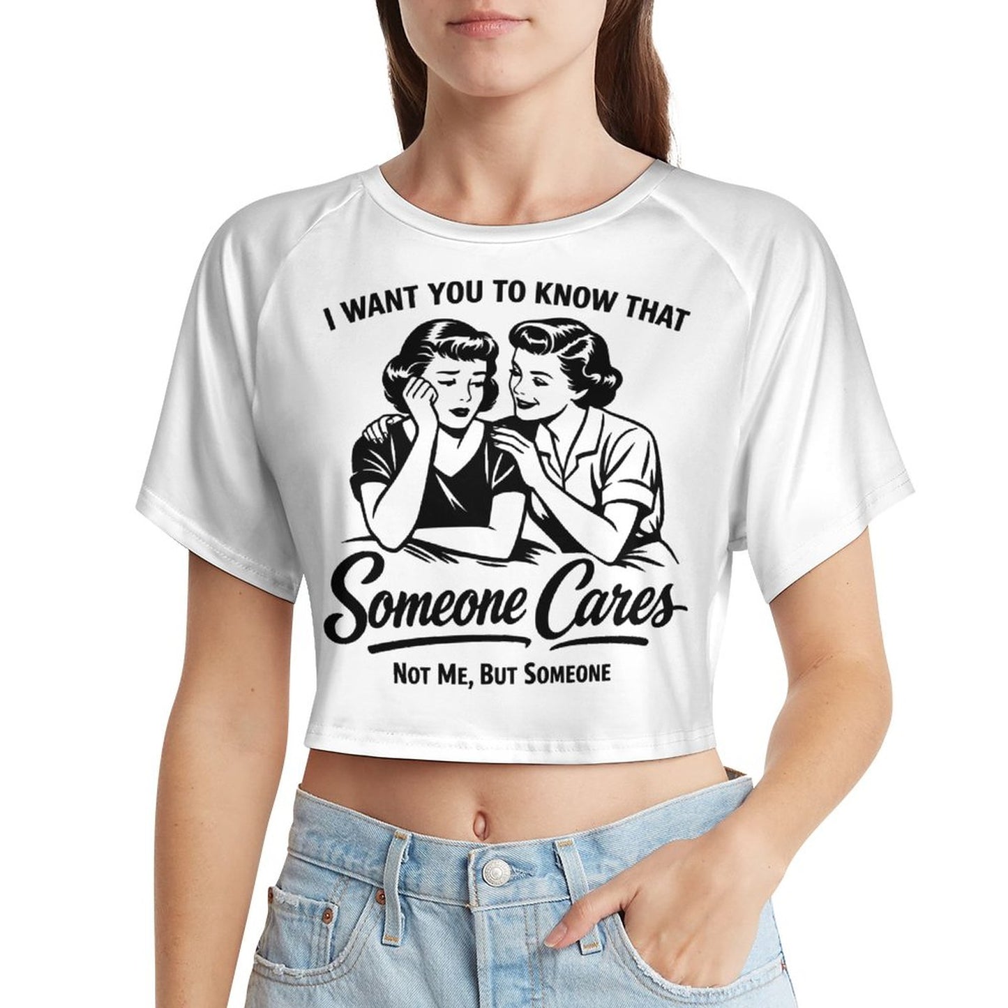 A young woman wearing a fitted white short sleeve baby tee crop top featuring a black vintage pop-art graphic of two women and the sarcastic quote I WANT YOU TO KNOW THAT Someone Cares NOT ME, BUT SOMEONE.