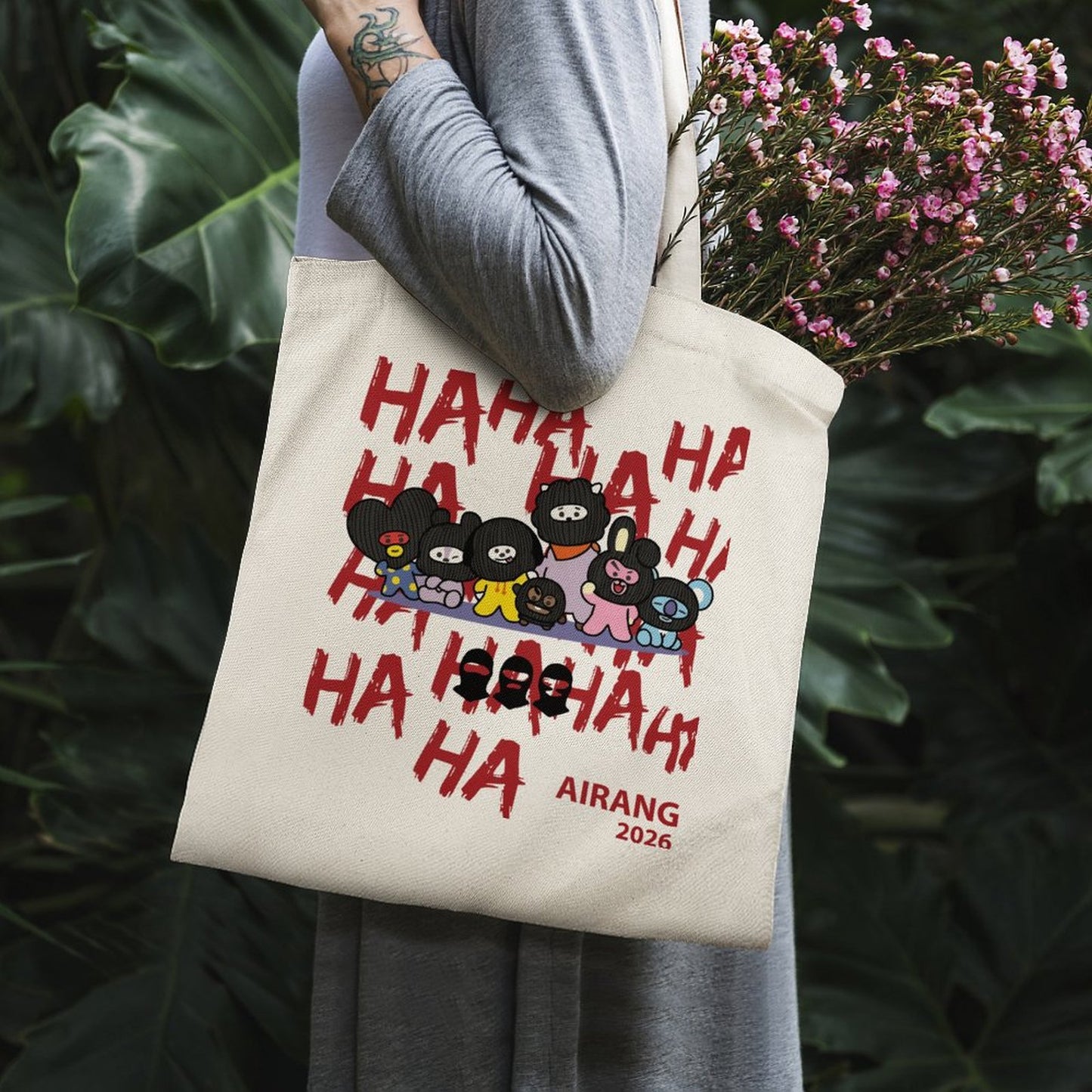 Aesthetic outdoor view of the BT21 Hooligan canvas tote bag resting against green leaves in natural sunlight.