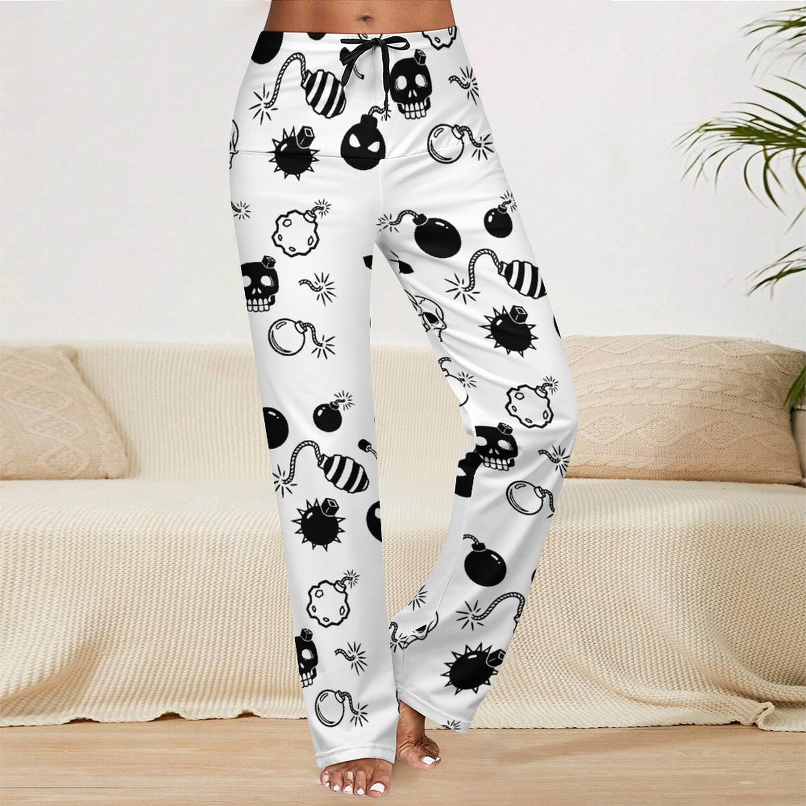 Front view of a model wearing white straight-leg drawstring yoga pants featuring an edgy, all-over graphic print of retro skulls and bombs for an alternative Y2K grunge streetwear look.