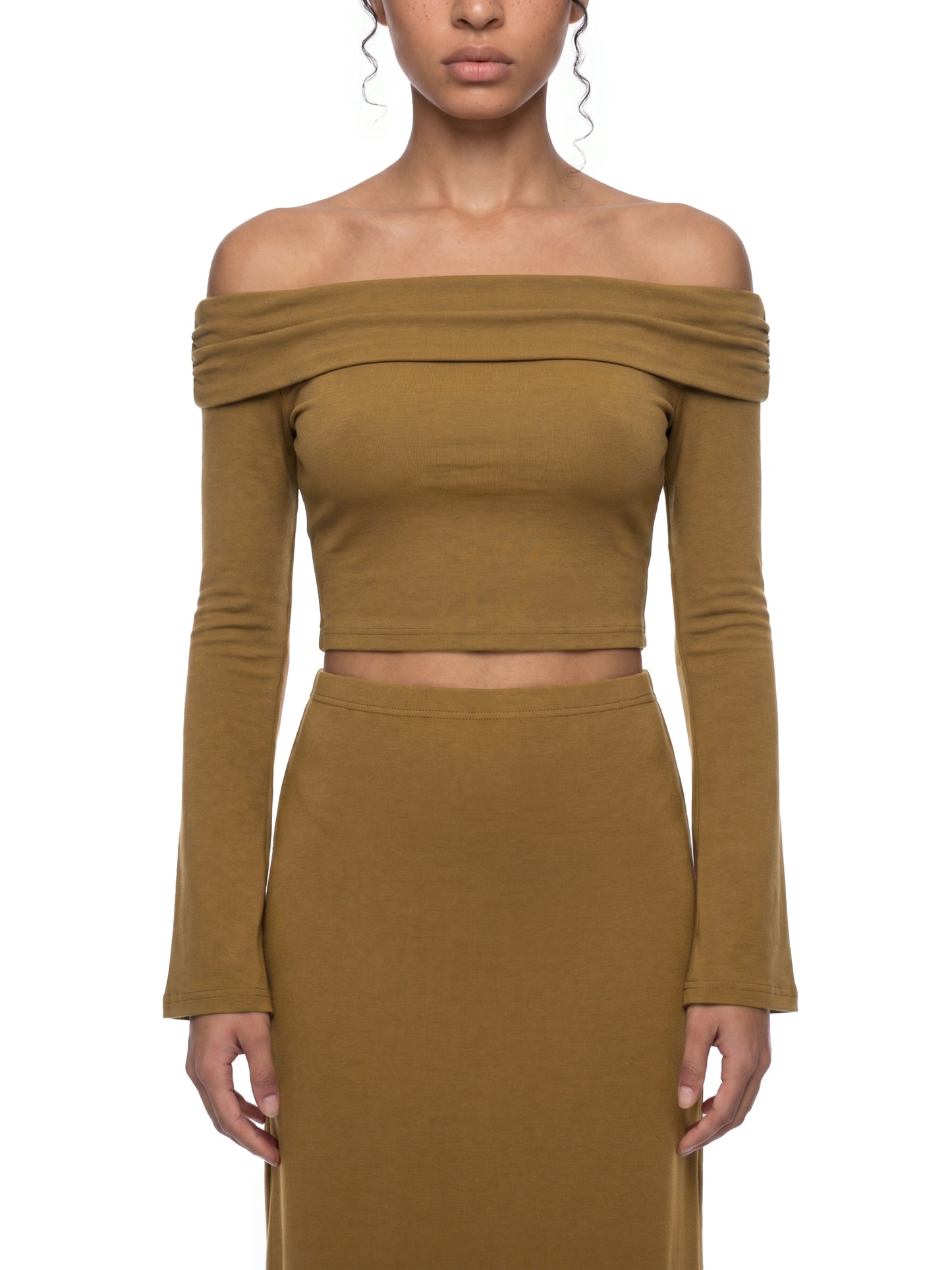 Front view of a model wearing the brown version of the BTS Arirang off-the-shoulder crop top, highlighting the elegant bardot neckline and long bell sleeves.