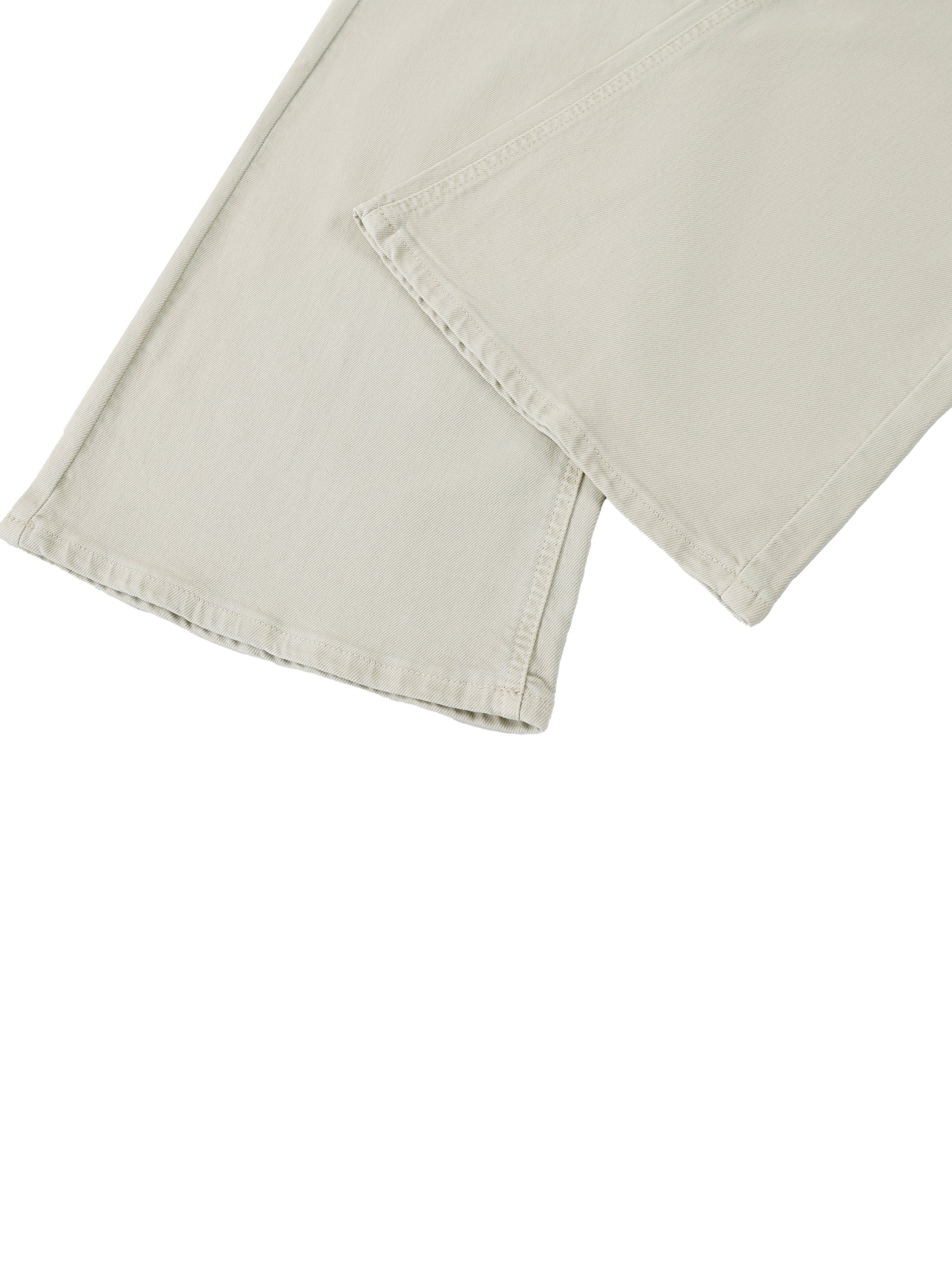 Close-up detail of the custom split-hem cut and stitched edge on the flared leg of women's beige vintage wash streetwear jeans.