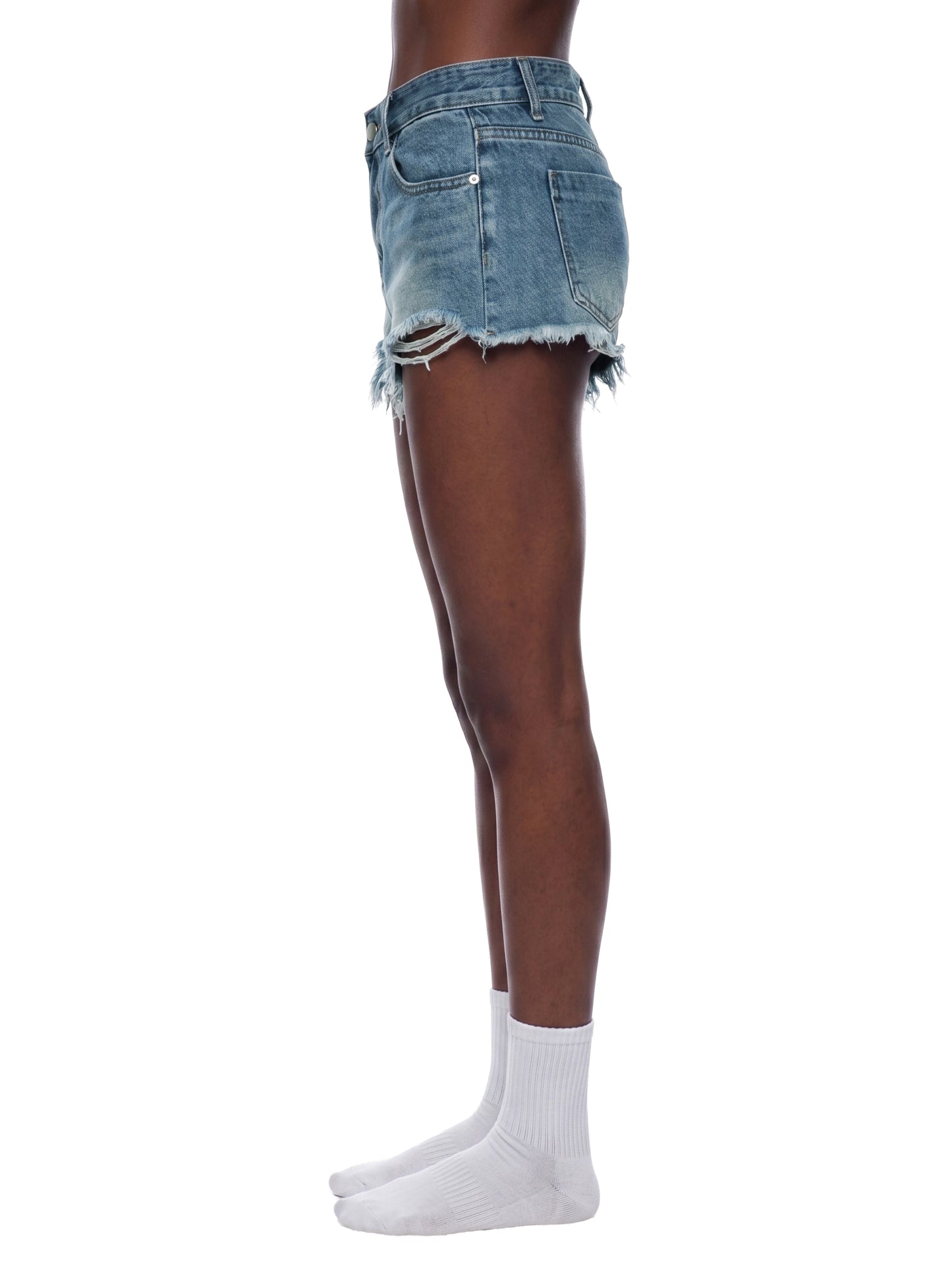 Side profile view of a model wearing the blue BTS vintage wash raw hem denim shorts, highlighting the short crop silhouette and distressed side seam details.