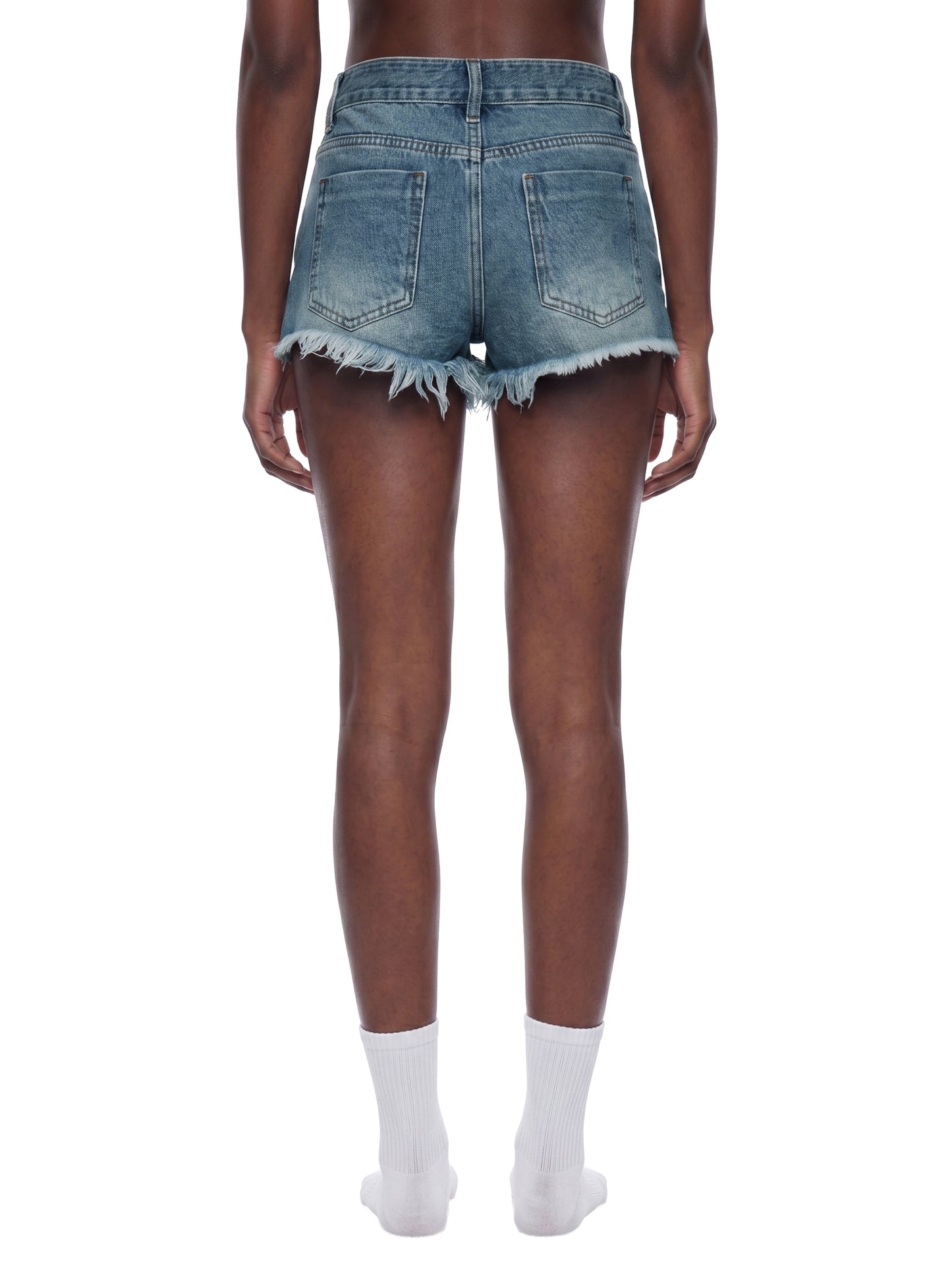 Rear view of a model wearing the blue BTS vintage wash raw hem denim shorts, showcasing the bodycon fit and frayed edge drape.