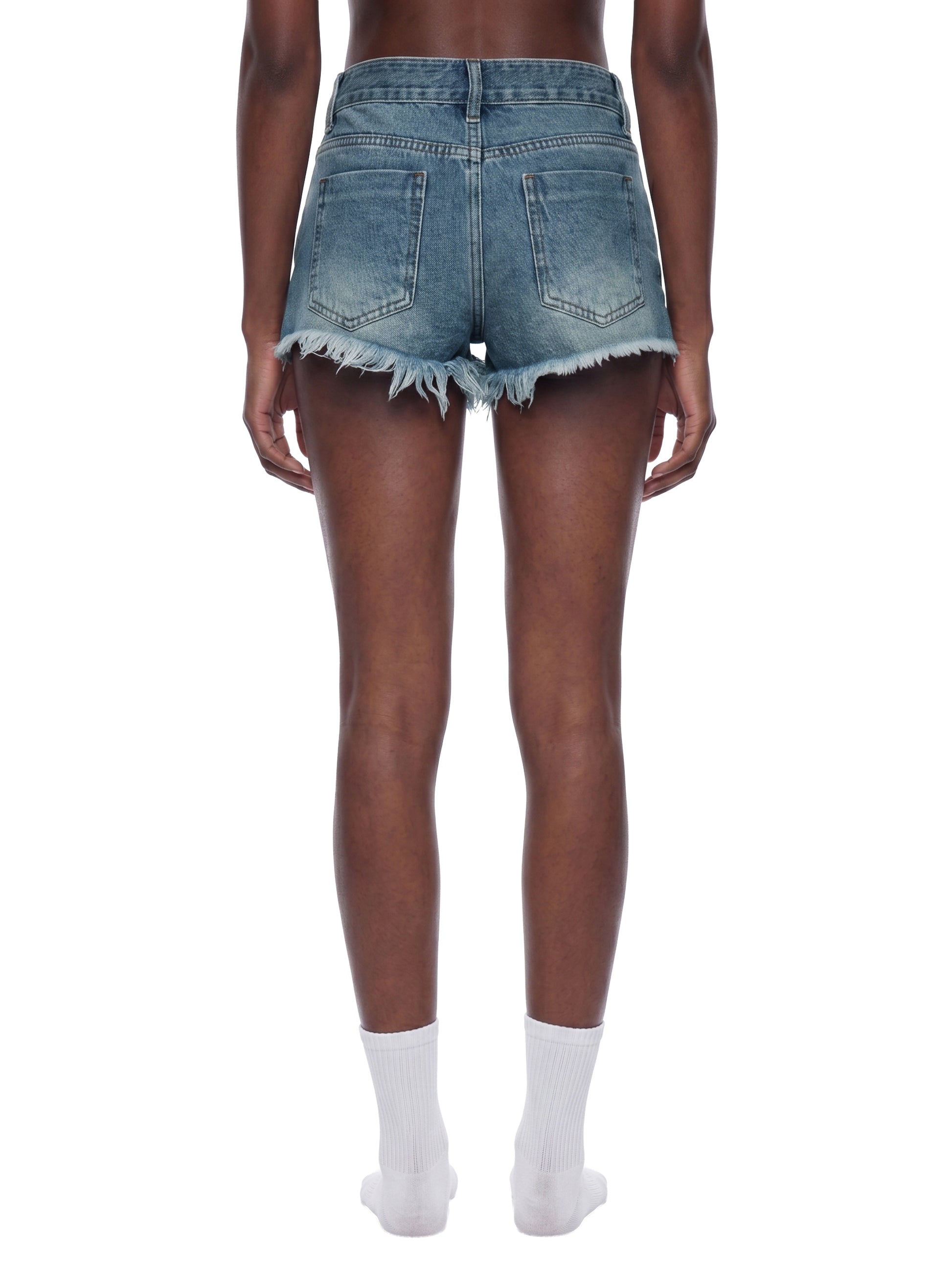 Rear view of a model wearing the blue BTS vintage wash raw hem denim shorts, showcasing the bodycon fit and frayed edge drape.