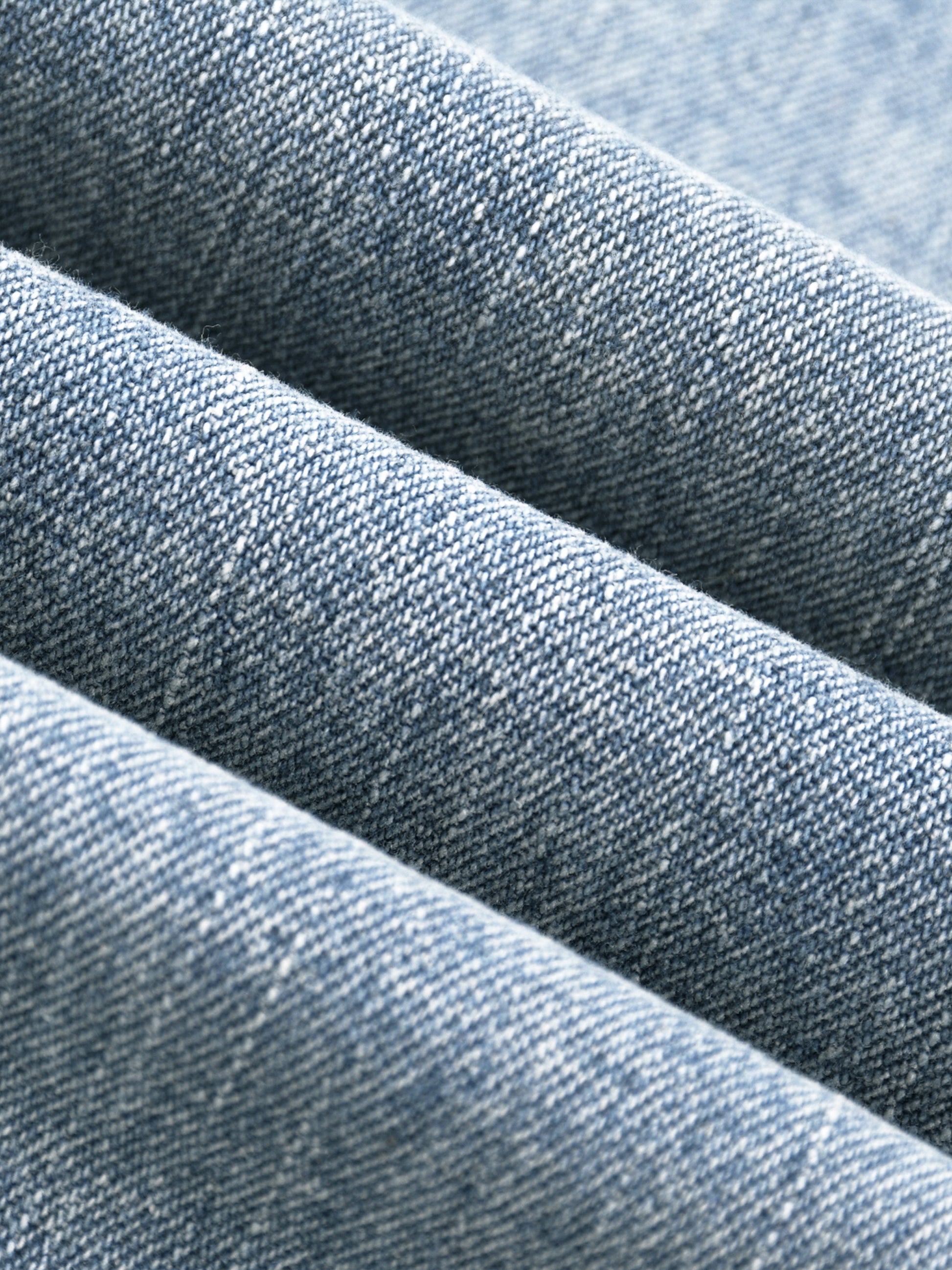 Macro close-up view of the premium heavyweight vintage wash denim fabric, highlighting the textured weave and dual-tone yarn fibers.